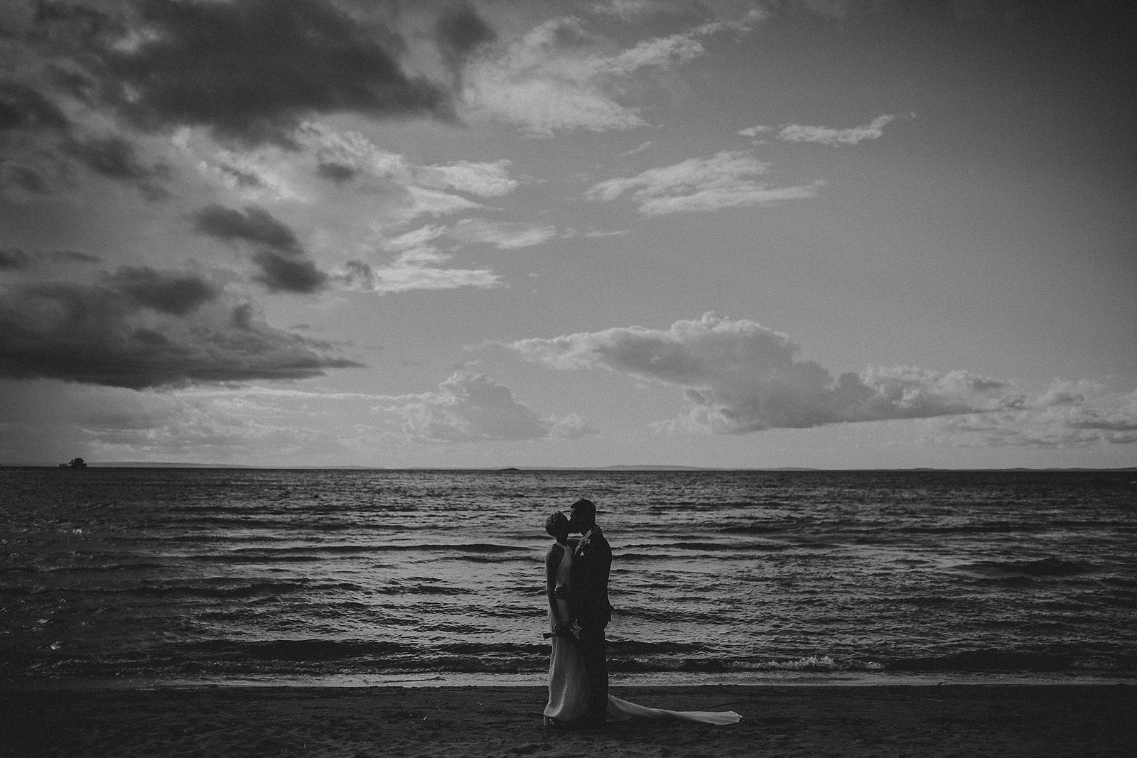 bride and groom kissing on the beach in Vadstena, Sweden