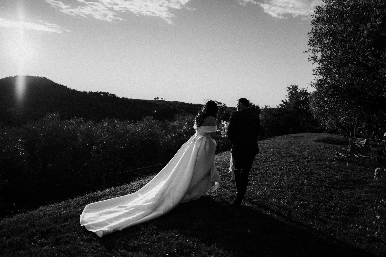 black and white wedding photo of a couple walking in sunset